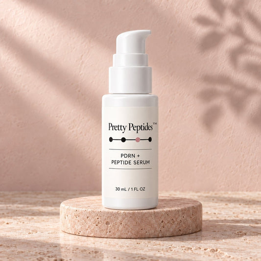 Pretty Peptides PDRN + Peptide Serum, 30 ml pump bottle on a travertine riser against a blush plaster wall