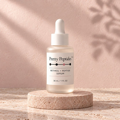 Pretty Peptides Retinol + Peptide Serum, 30 ml frosted dropper bottle on a travertine riser against a blush plaster wall