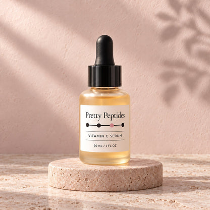 Pretty Peptides Vitamin C Serum, 30 ml amber dropper bottle on a travertine riser against a blush plaster wall